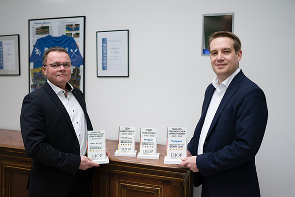 Top employer awards Two employees in suits smilingly present the awards for Knüppel and Excor.